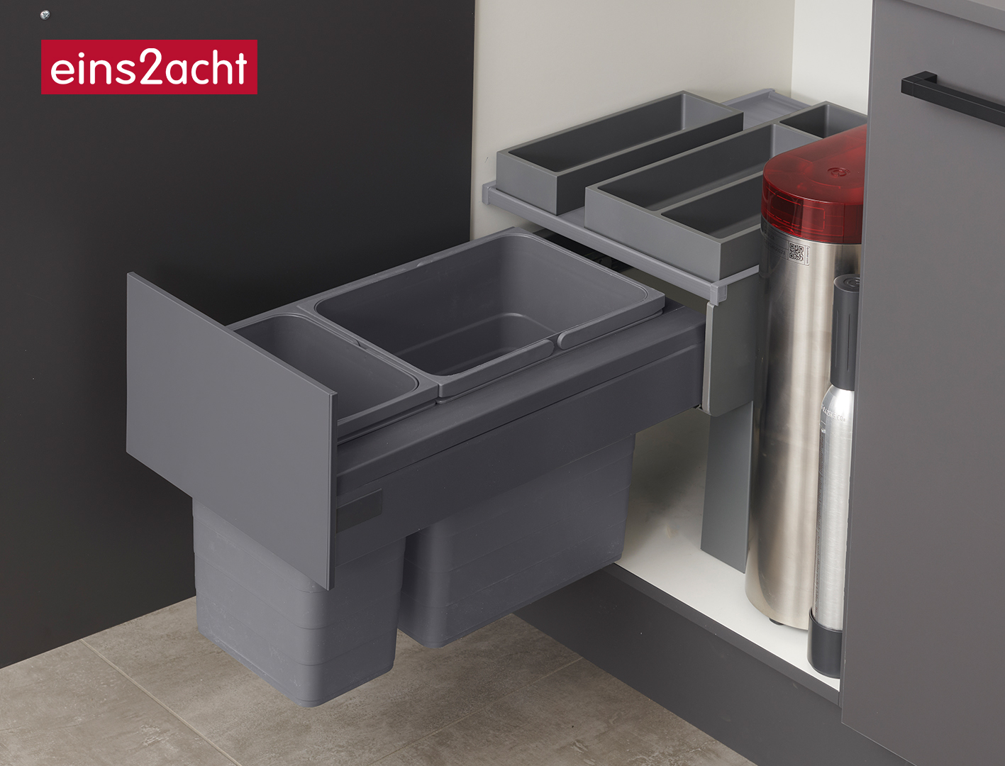 eins2acht Abfallbehälter hinter einer Drehtür neben einem Wasseraufbereitungssystem